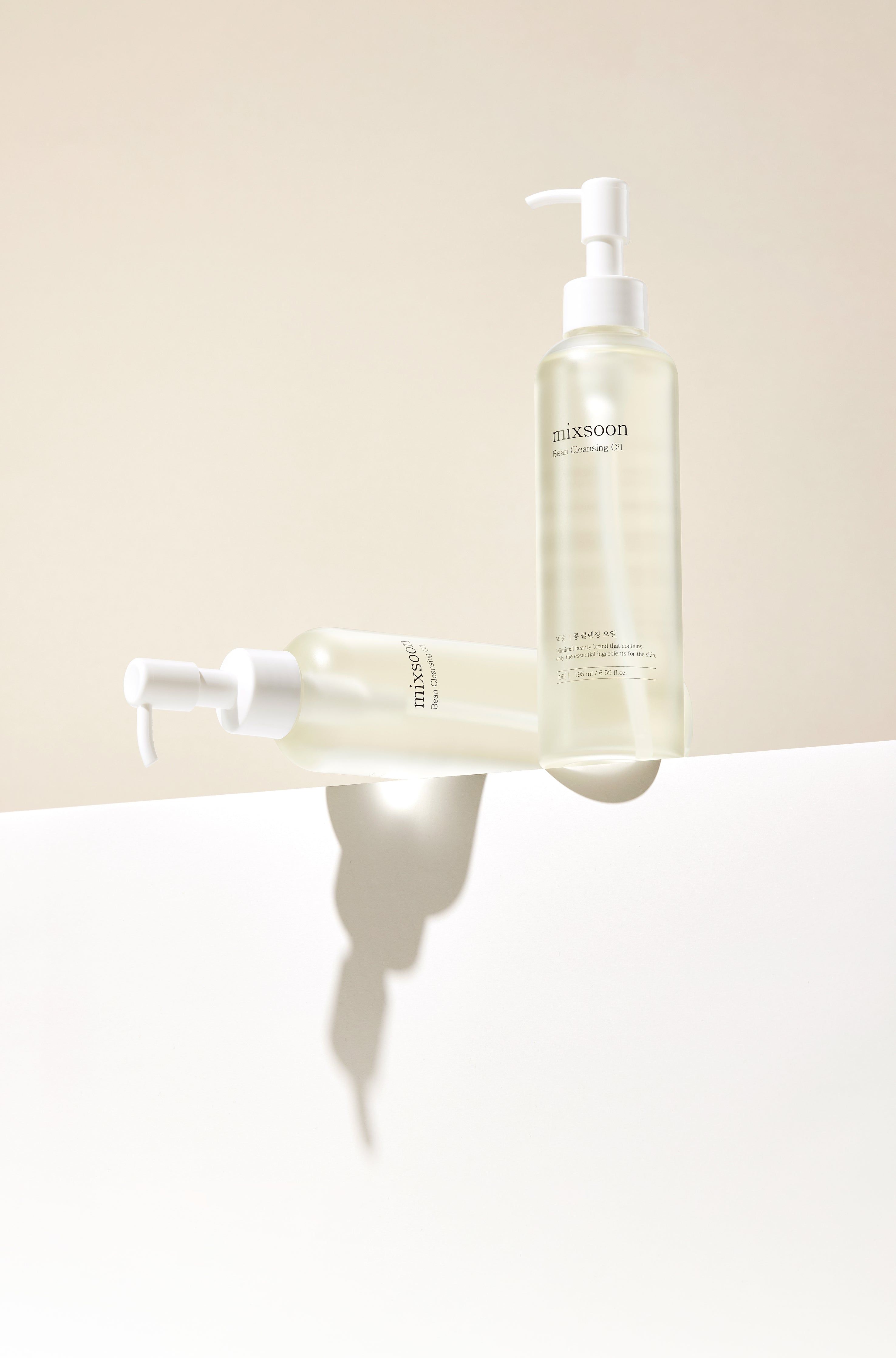 Zwei Flaschen mixsoon Bean Cleansing Oil auf einer weißen Oberfläche mit Schatten.