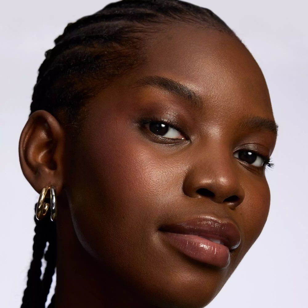 Porträt einer Frau mit dunkler Haut. Sie trägt goldene Creolen. Lippen glänzend.