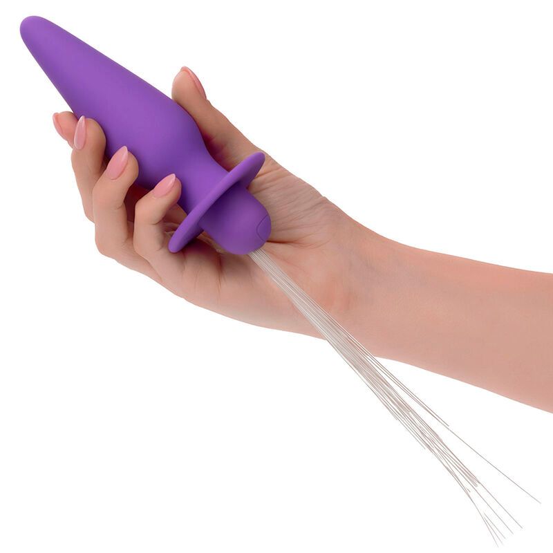 Hand hält lila Analstecker. Konische Form, breite Basis, weiße Fasern.