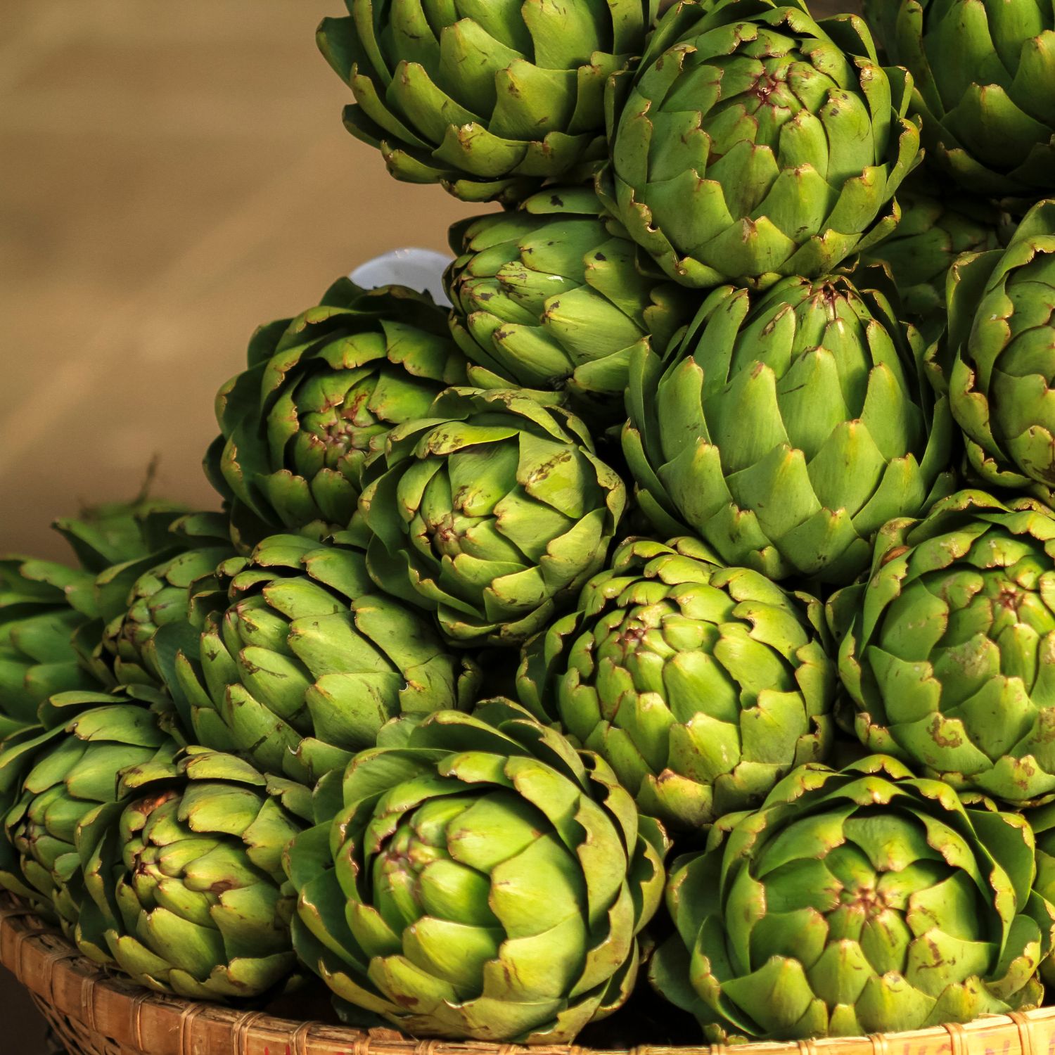 Haufen grüner Artischocken in einem Korb. Nahaufnahme, Draufsicht.