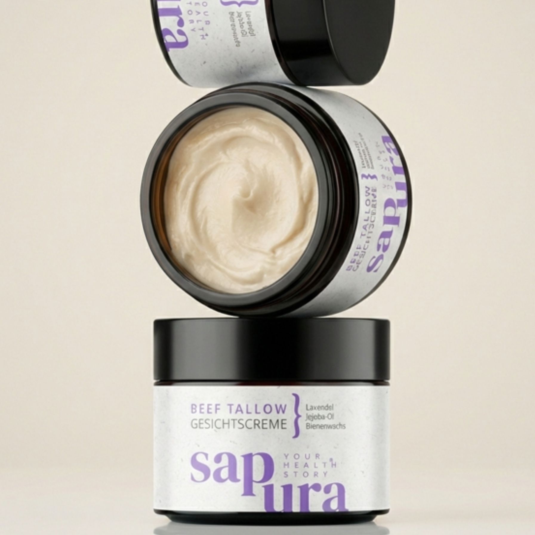 Drei Creme-Tiegel gestapelt. Aufschrift: Beef Tallow Gesichtscreme, sapura. Offene Tiegel mit Creme.