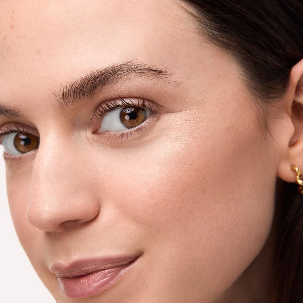 Nahaufnahme eines Gesichts mit aufgetragenem Highlighter. Hautton und Augenfarbe sind sichtbar.