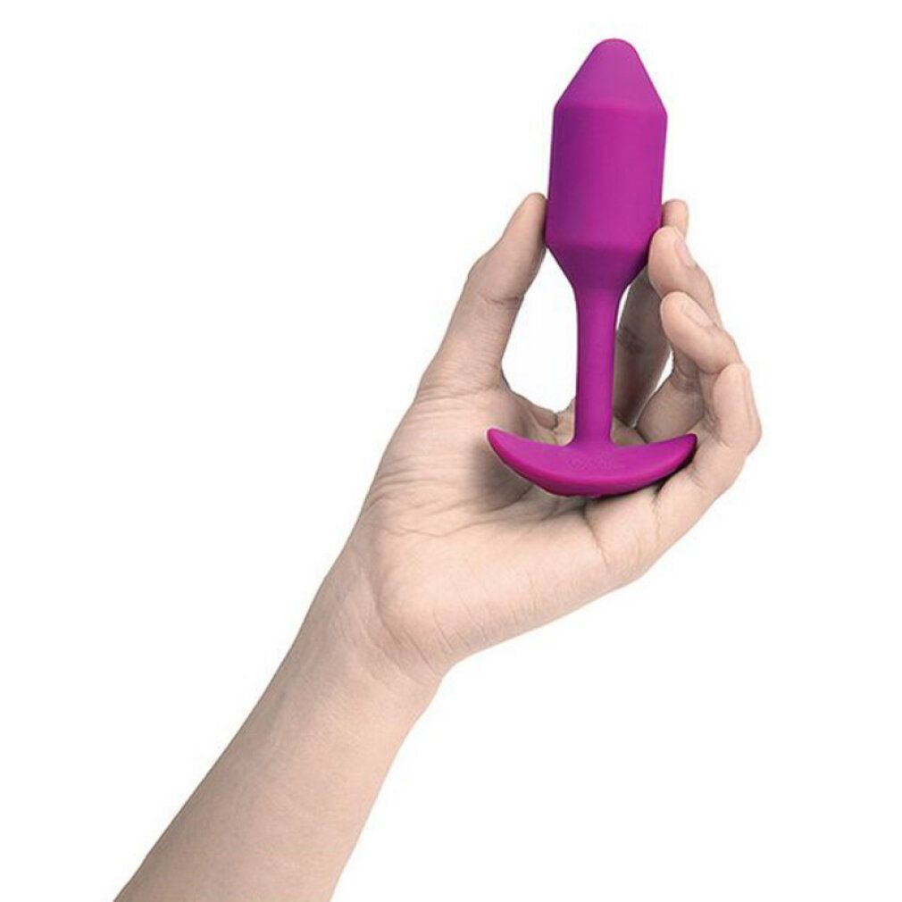 Hand hält einen rosa Plug. Kegelförmiger Kopf, Stiel und breite Basis. Weißer Hintergrund.