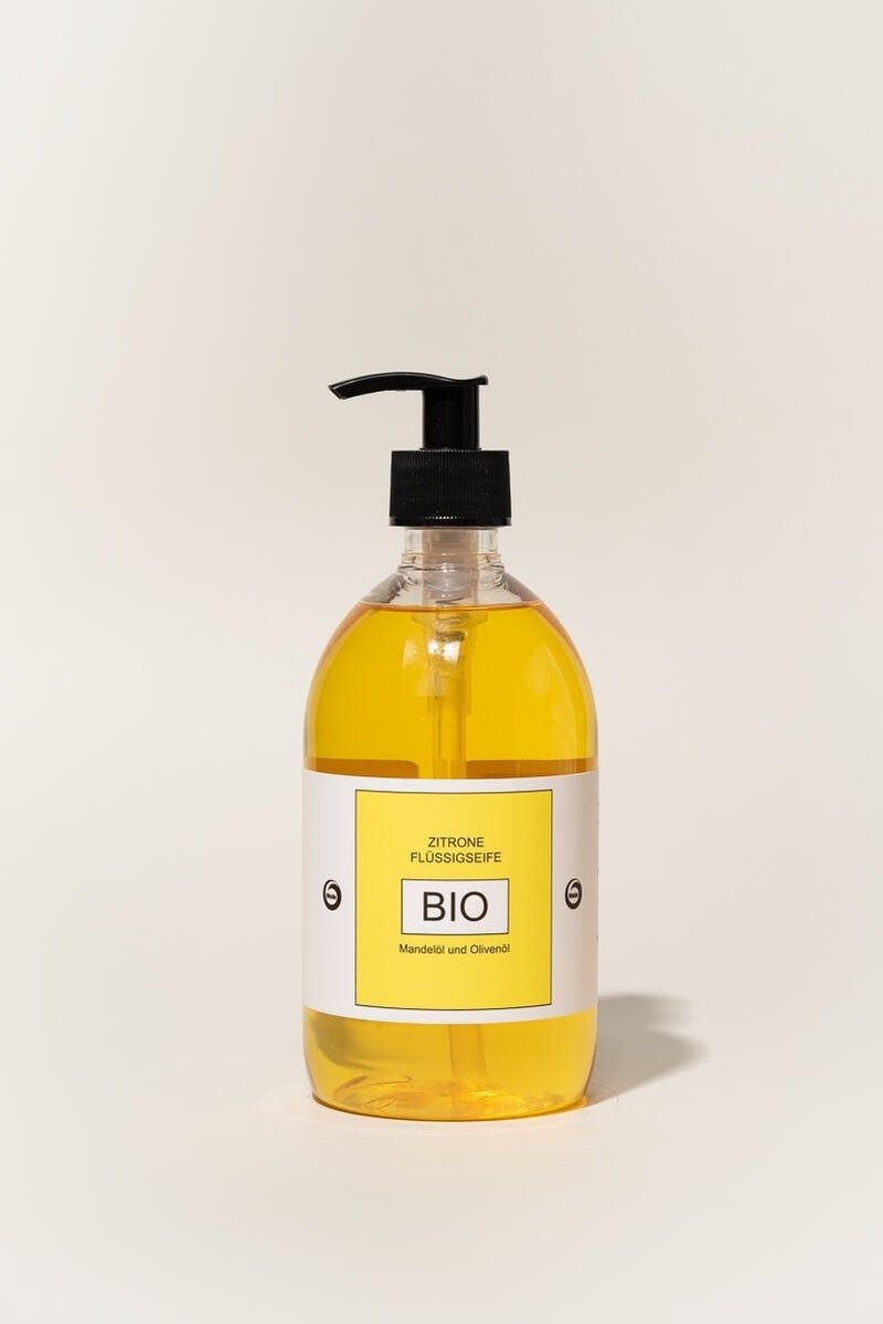 Zitronen-Flüssigseife in einer transparenten Flasche mit schwarzem Spender. Gelbe Flüssigkeit, gelbes Etikett mit BIO-Aufdruck.