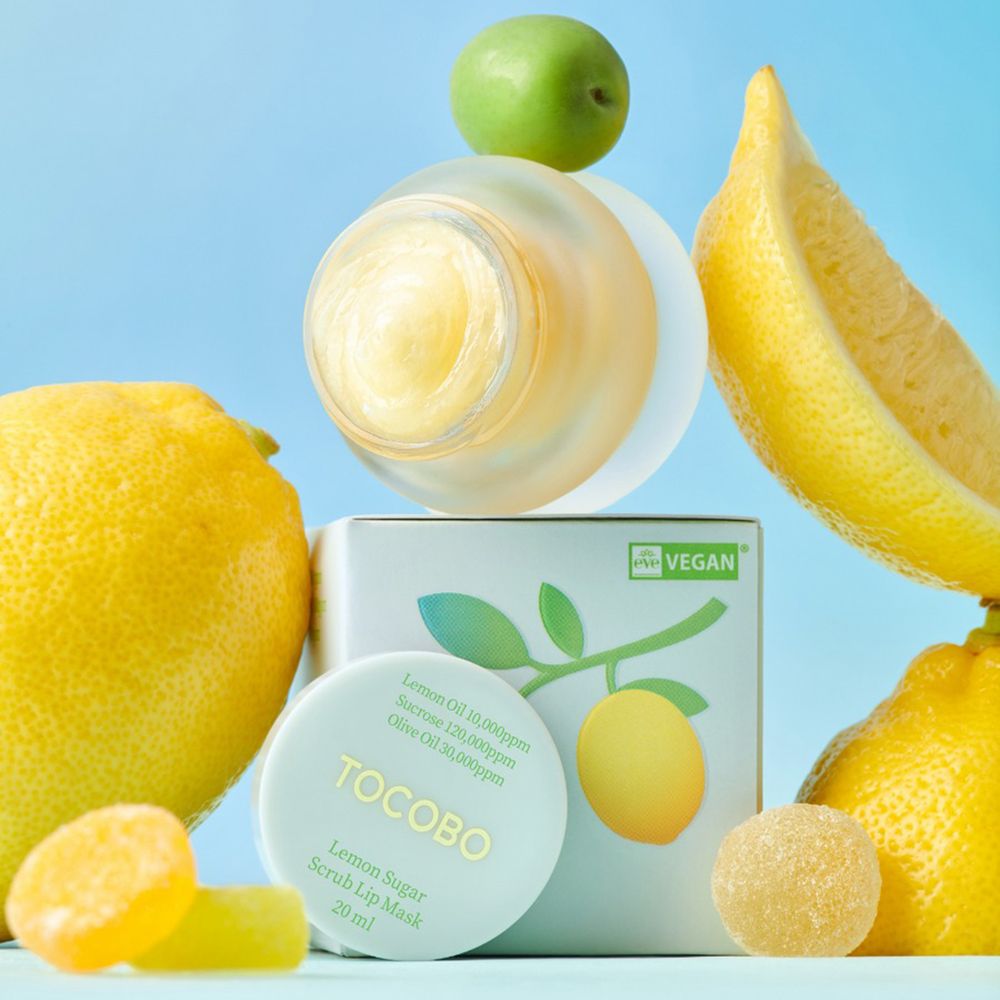 Produkt mit Verpackung, Zitronen und Süßigkeiten. Auf der Verpackung steht "TOCOBO Lemon Sugar Scrub Lip Mask".