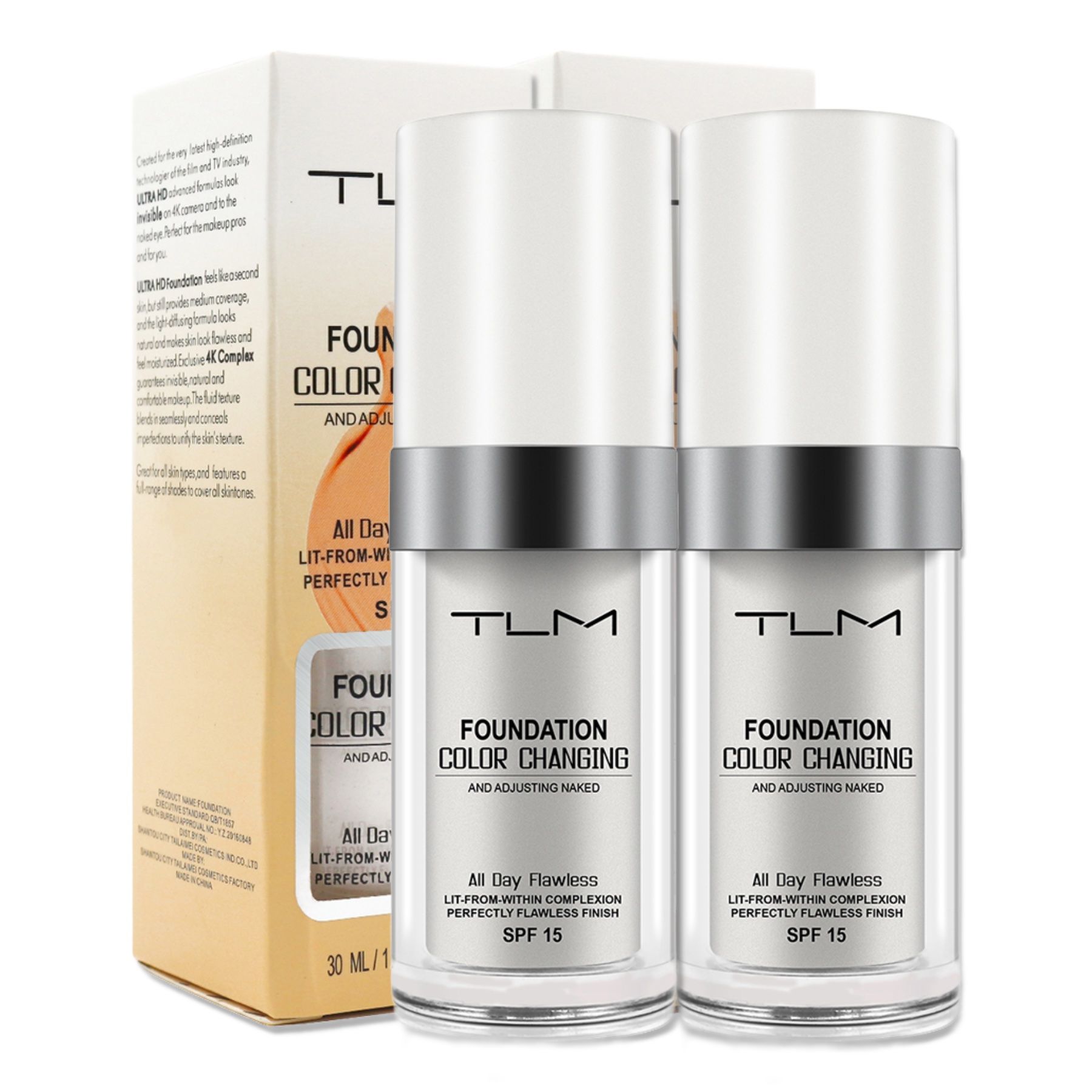 Zwei Flaschen Foundation mit weißem Deckel und silbernem Ring. Aufschrift: TLM Foundation Color Changing SPF 15. Verpackung.