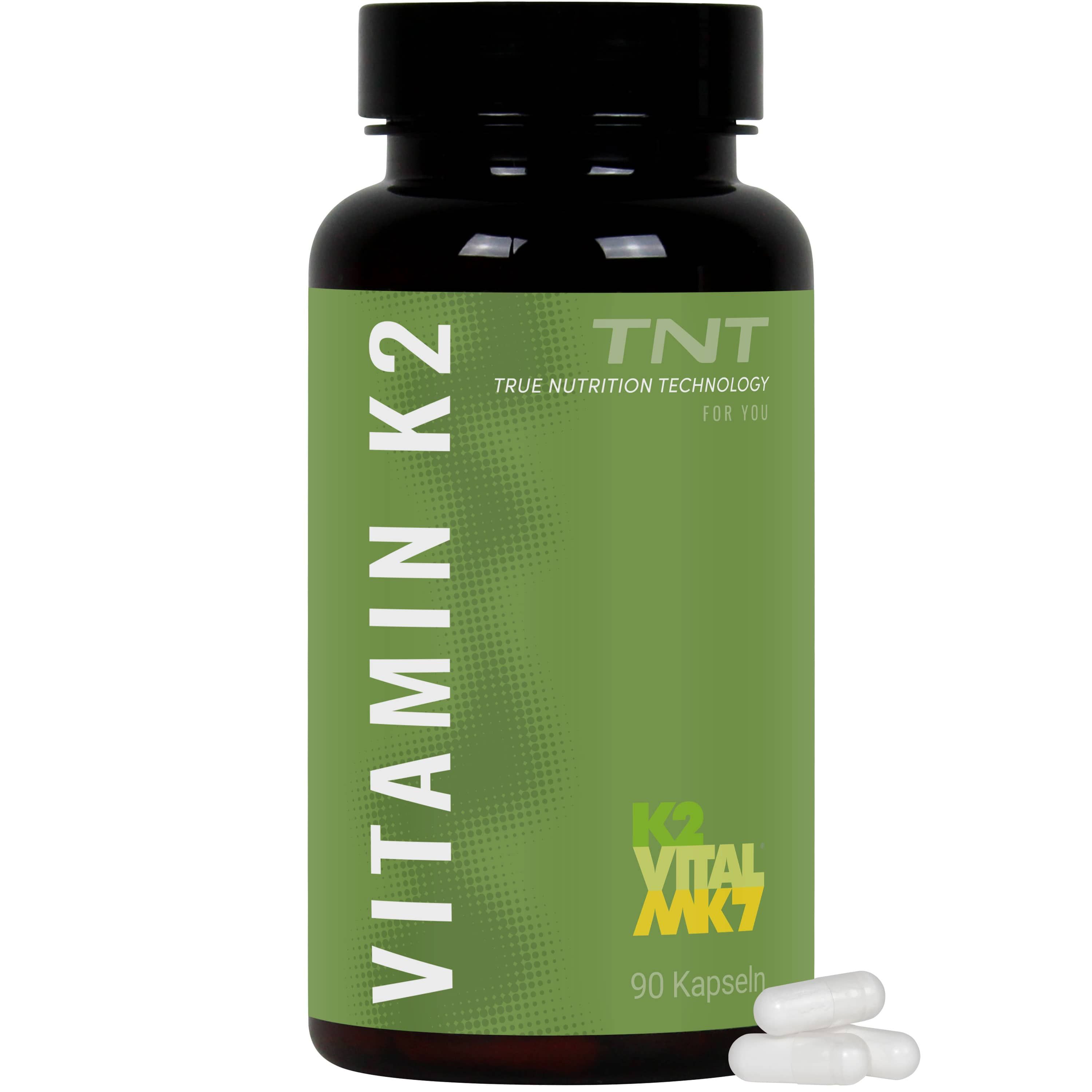 Braune Flasche mit grüner Etikett. Aufschrift: Vitamin K2, K2 Vital MK7, 90 Kapseln. Weiße Kapseln liegen daneben.