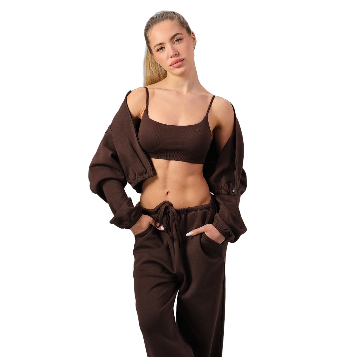 Frau in brauner Sportbekleidung: Crop-Top, Jacke und Jogginghose.