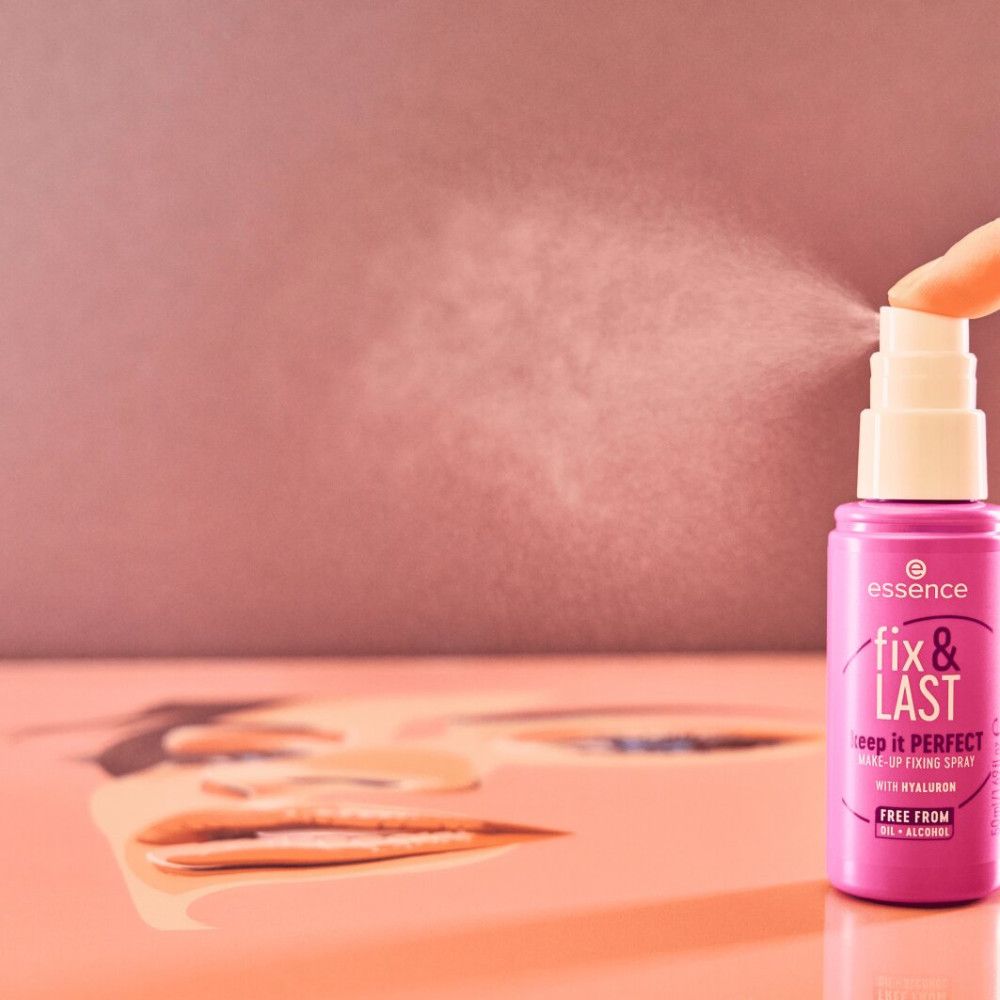 Rosa Make-up Fixierspray-Flasche sprüht. Schriftzug: Essence, fix & LAST, keep it PERFECT, mit Hyaluron, FREE FROM. Hintergrund: Gesichtsskizze.