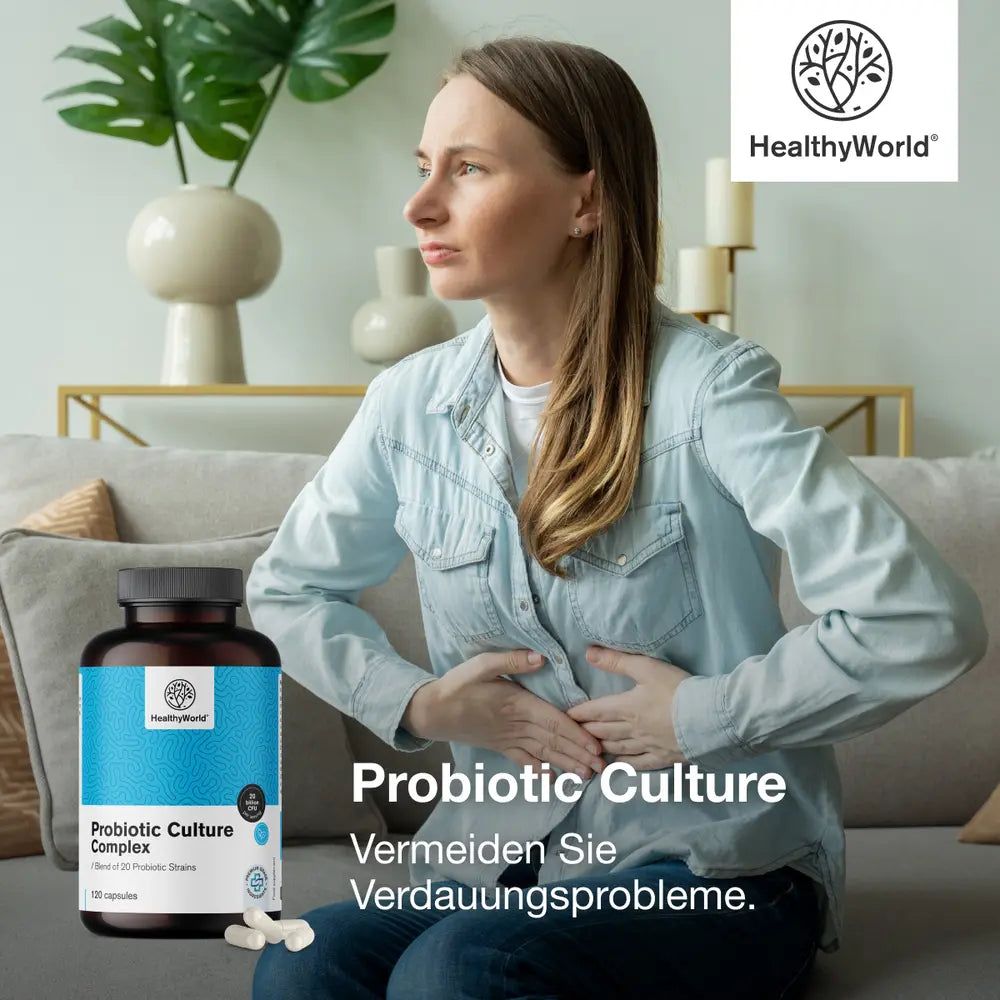 Frau hält sich den Bauch. Neben ihr steht eine Flasche mit Kapseln. Aufschrift: Probiotic Culture Complex.
