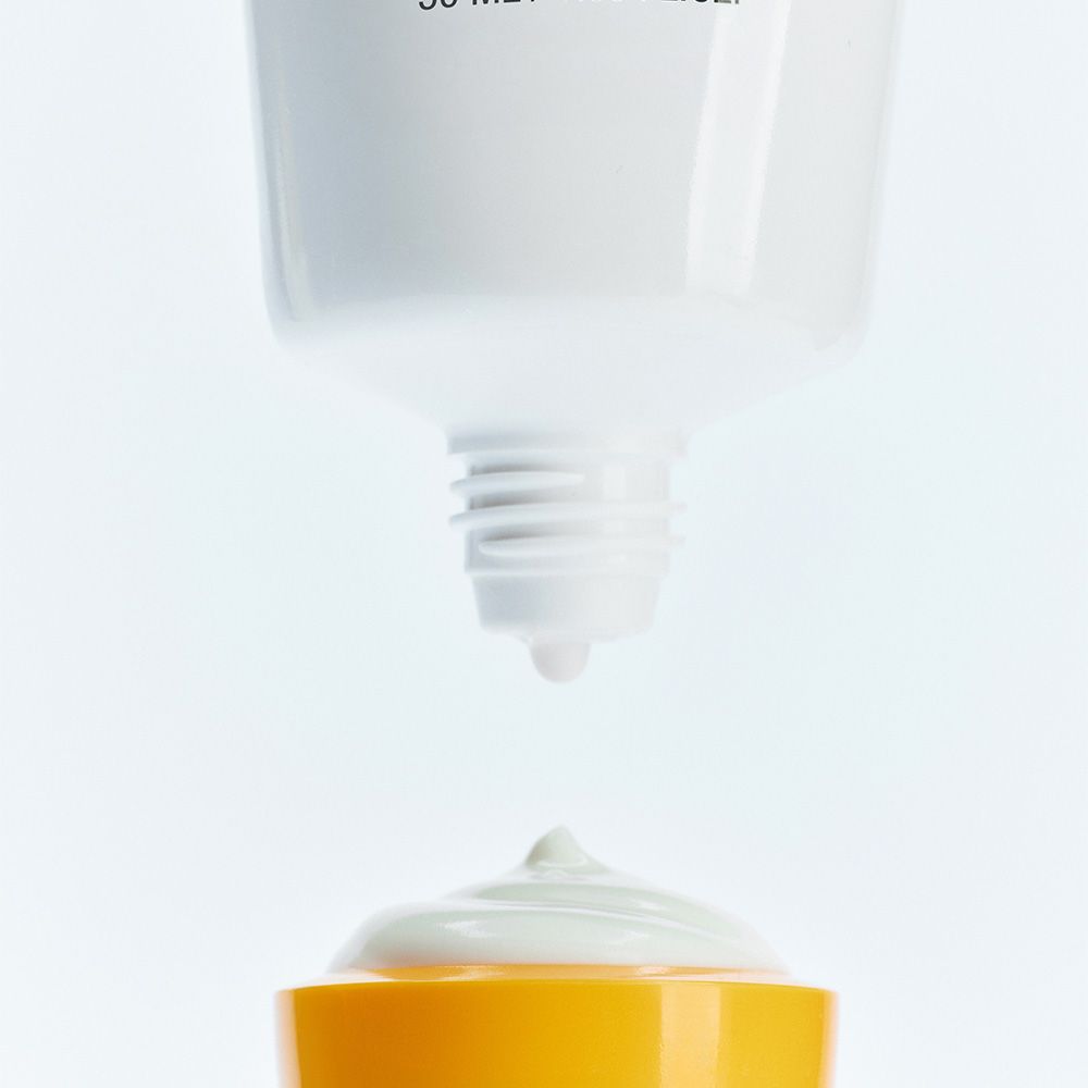 Nahaufnahme des Auslasses einer Sonnenschutzmittel-Tube, mit einem Tropfen Creme.