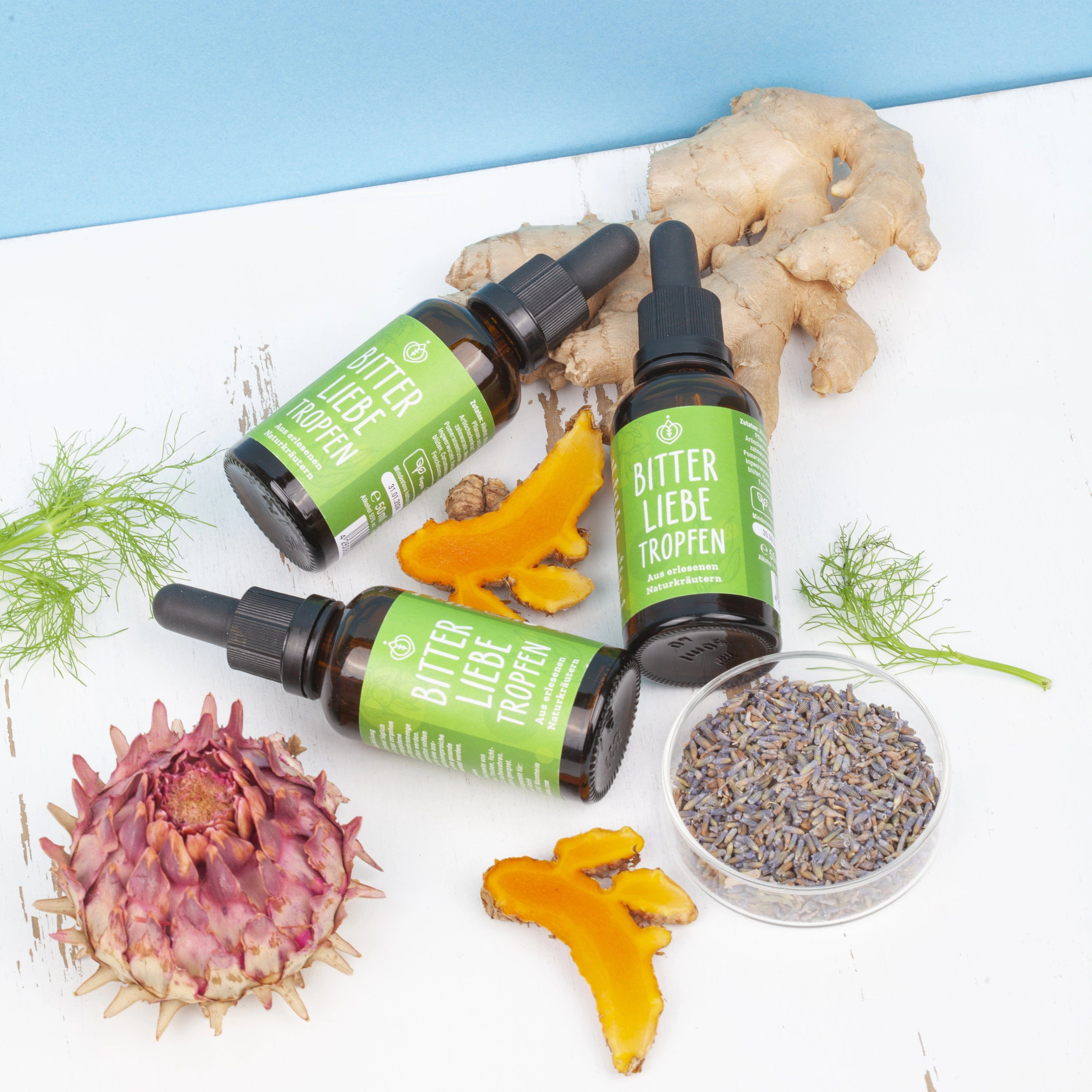 Drei Flaschen BitterLiebe Tropfen. Braune Flaschen mit schwarzer Pipette. Auf weißem Hintergrund.