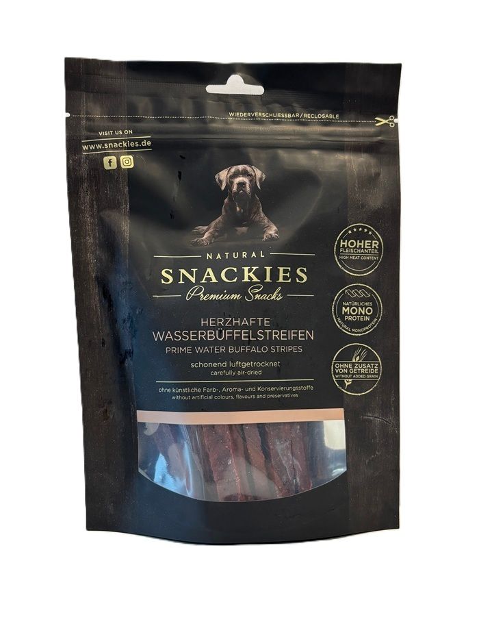 Verpackung mit Snackies Herzhafte Wasserbüffelstreifen. Schwarze Tüte mit Produktnamen, Hundefoto und Sichtfenster mit Streifen.