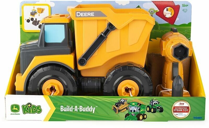 Gelber Kipplaster im Karton. Schwarze Reifen, graue Kabine, blaue Fenster. "DEERE" und "Build-A-Buddy" Schriftzug.