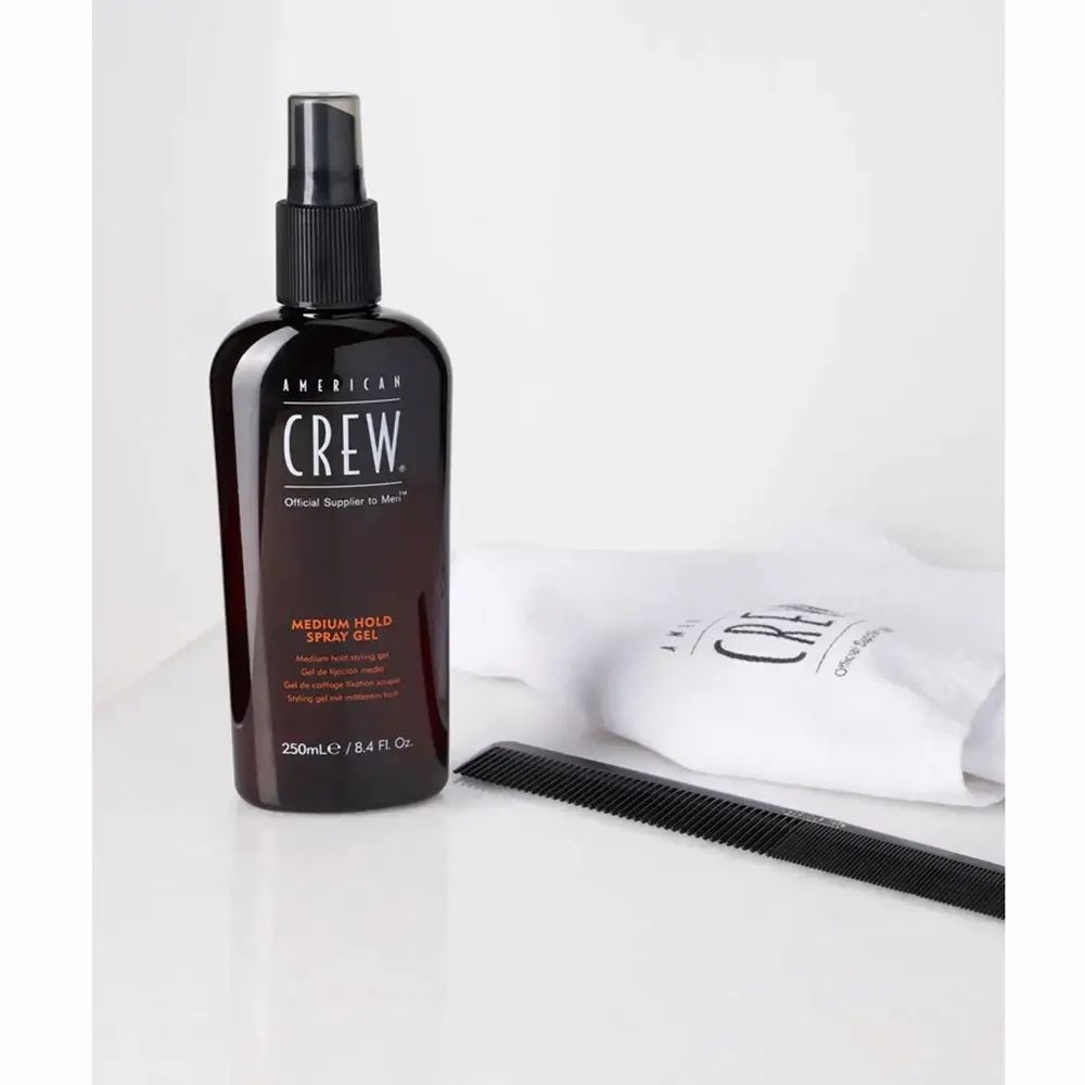 Braune Flasche mit Sprühkopf. AMERICAN CREW, MEDIUM HOLD SPRAY GEL. Kamm und Beutel mit Logo.