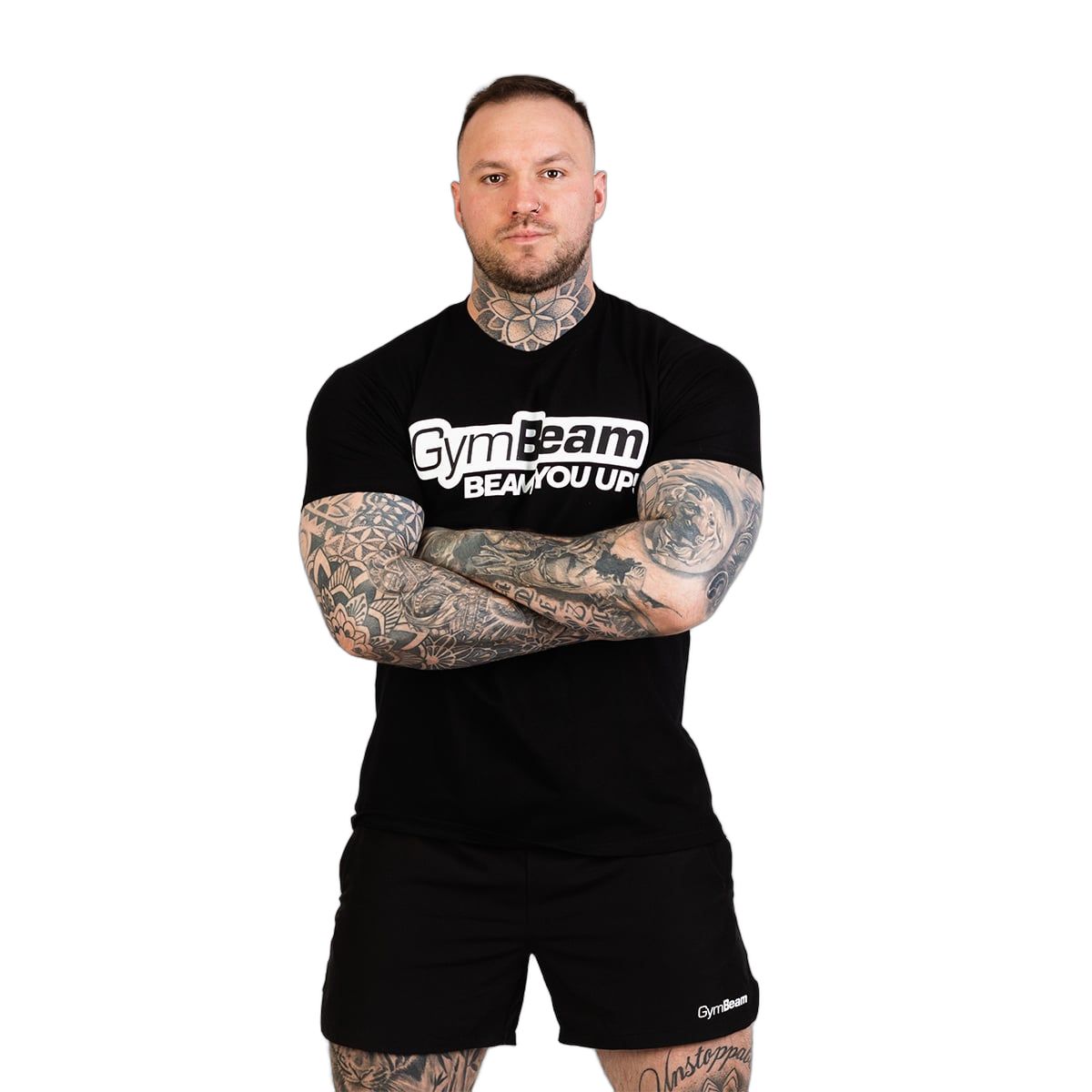 Mann in schwarzem GymBeam T-Shirt und Shorts, Arme verschränkt.