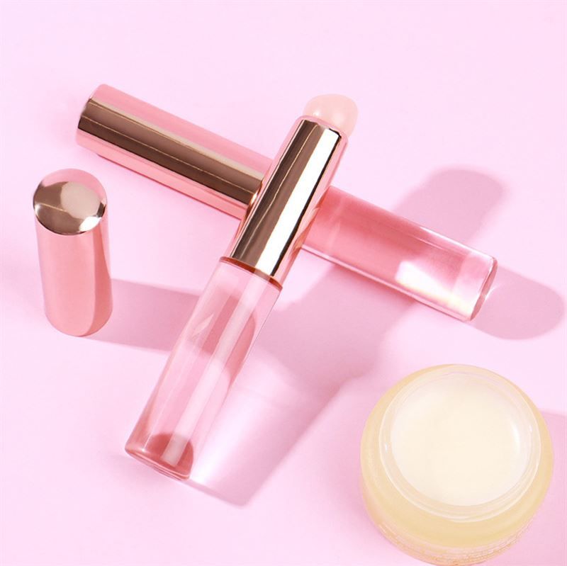 Zwei Pinsel, ein Deckel und ein Tiegel auf rosa Untergrund. Pinsel mit rosa Griff und hellem Applikator.