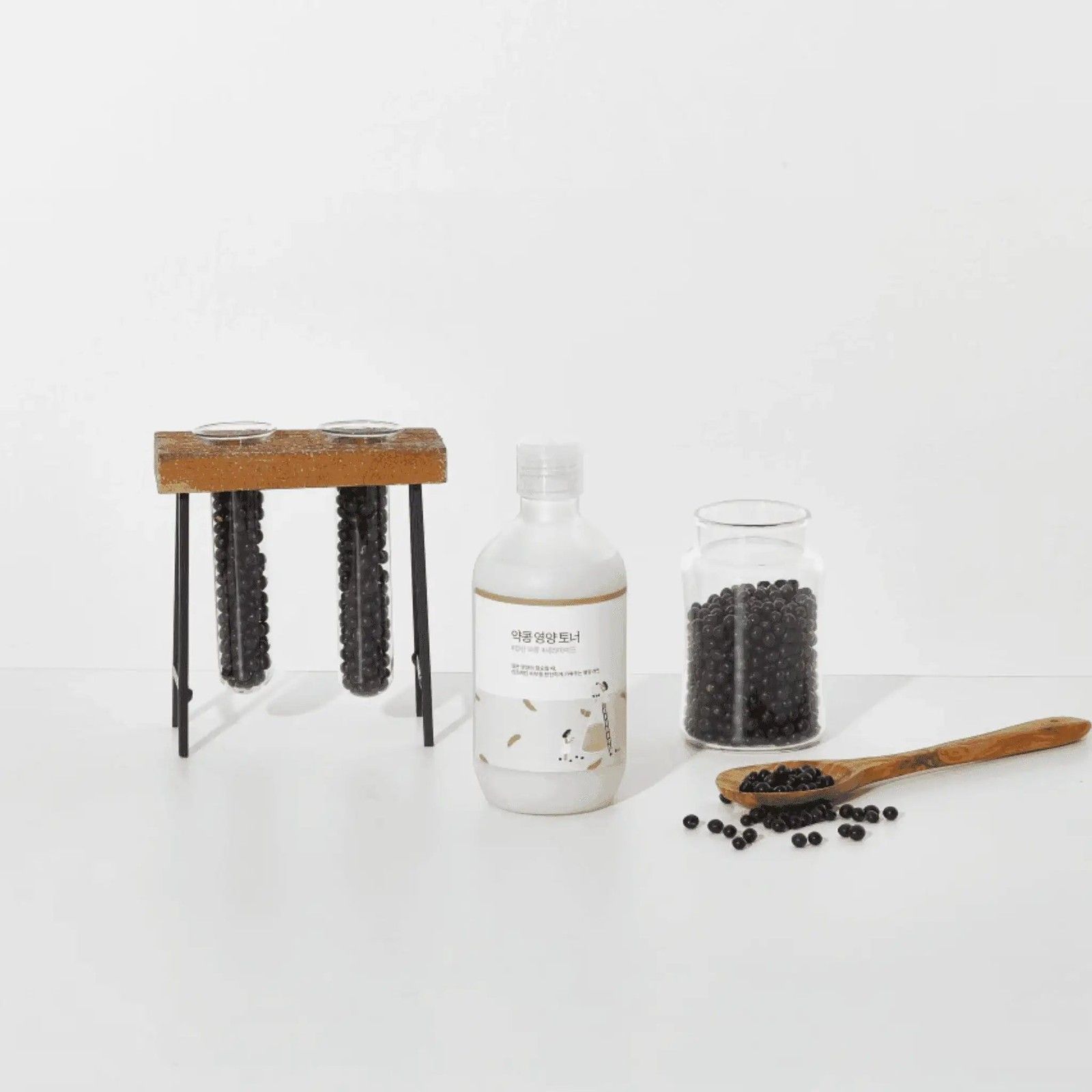 ROUND LAB Soy Bean Nourishing Toner Flasche neben einem Glas mit Sojabohnen und einem Holzlöffel.
