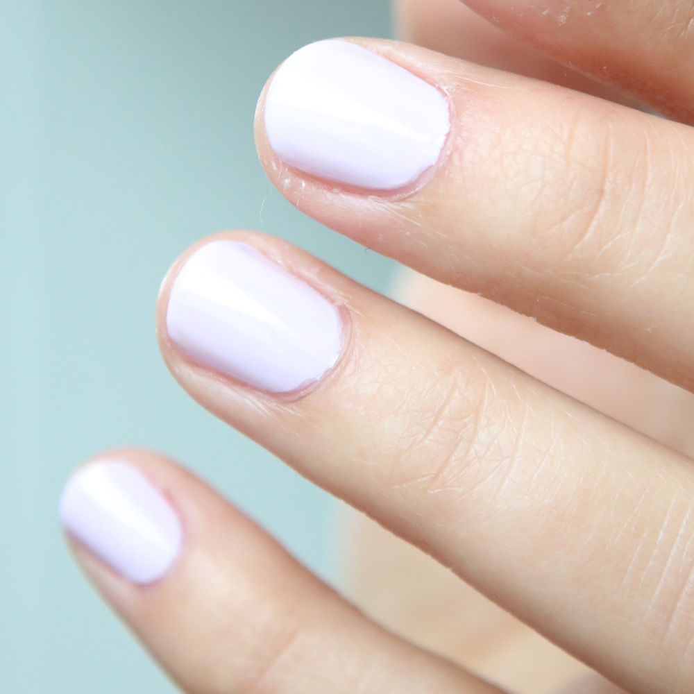 Nahaufnahme von Fingern mit helllila Nagellack. Die Nägel sind kurz und lackiert.