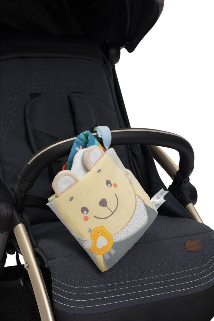 Weiches Aktivitätsbuch an einem Kinderwagen befestigt. Buch mit Bärenmotiv. Gelb, grau und blau. Mit Aufhängung.