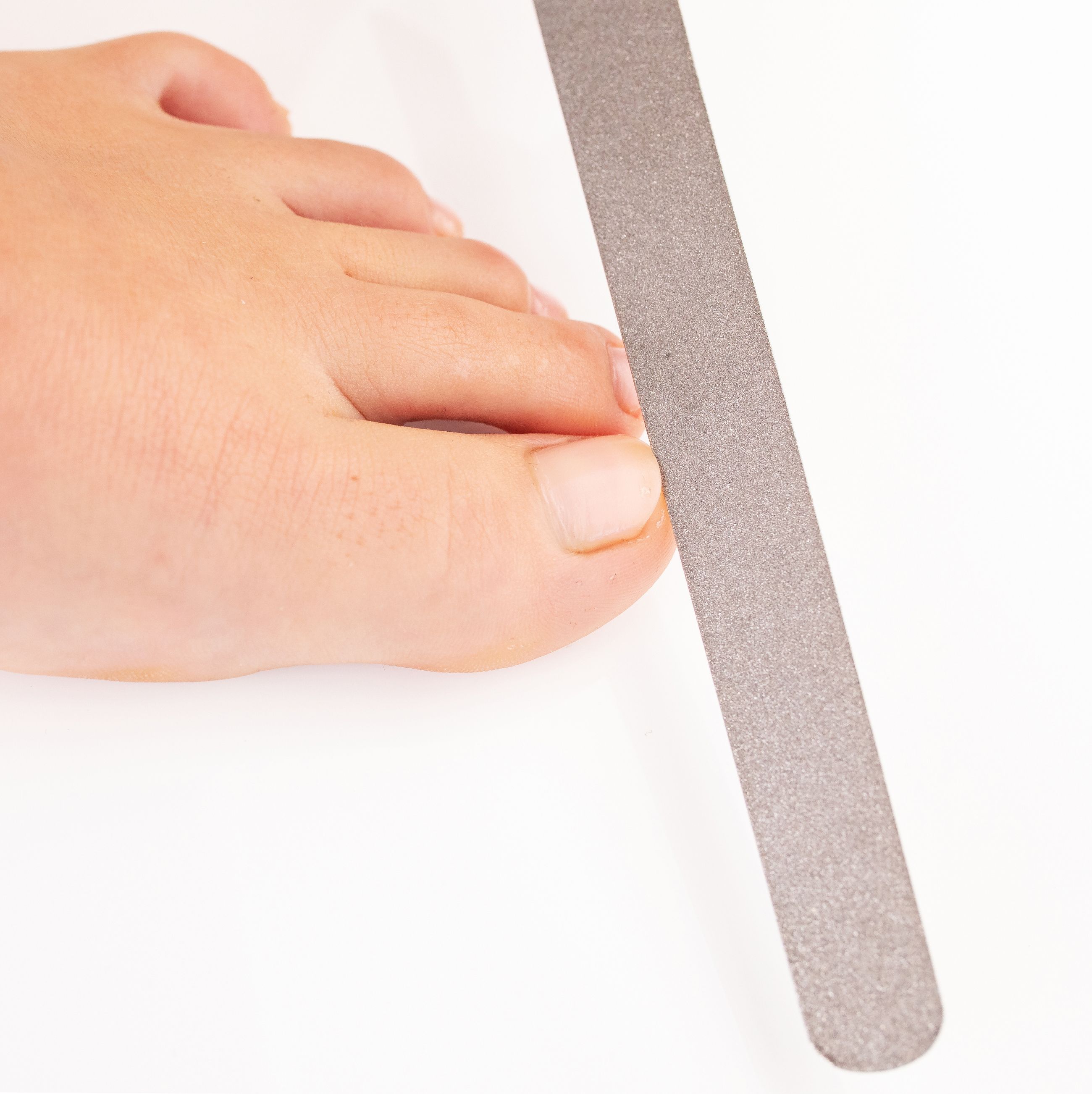 REMOS Diamantnagelfeile, sehr grob/fein, 20 cm. Nahaufnahme eines Zehs, Person feilt Zehennagel.