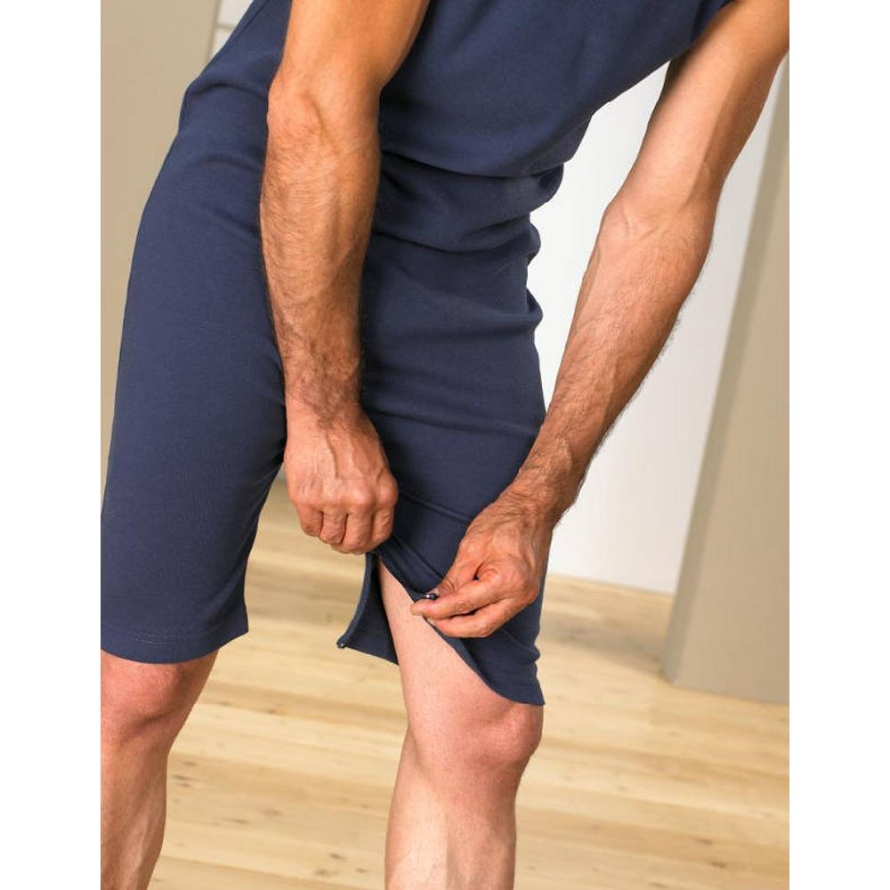 Nahaufnahme eines blauen Overalls ohne Arme. Reißverschluss an der Beinseite. Person öffnet den Reißverschluss.