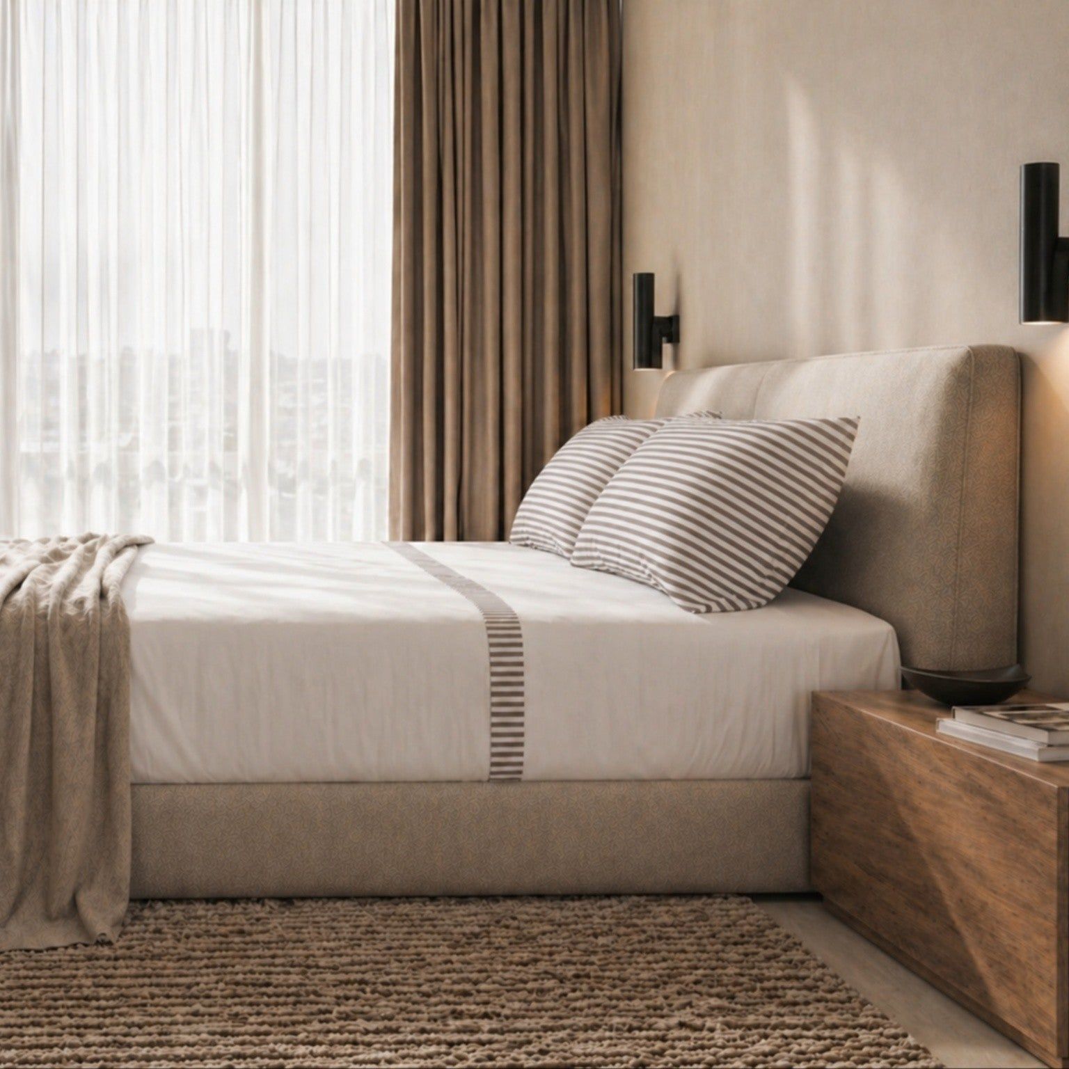Gemütlich gemachtes Bett mit gestreiften Kissen und Decke.